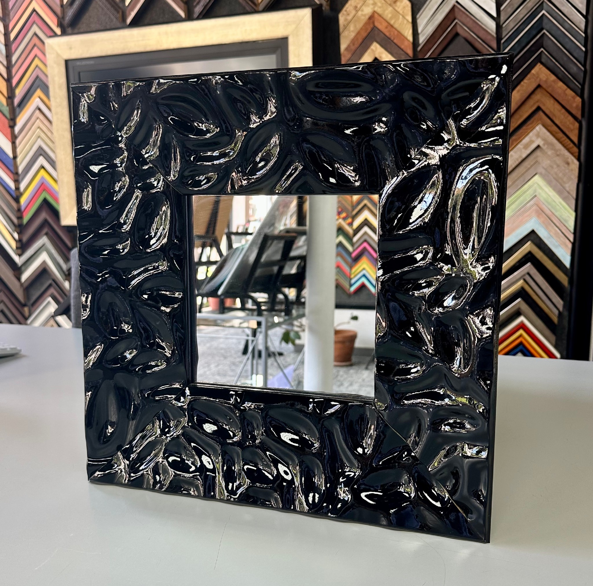 Custom framed mirror with a high-gloss black sculpted frame showcasing a bold contemporary design