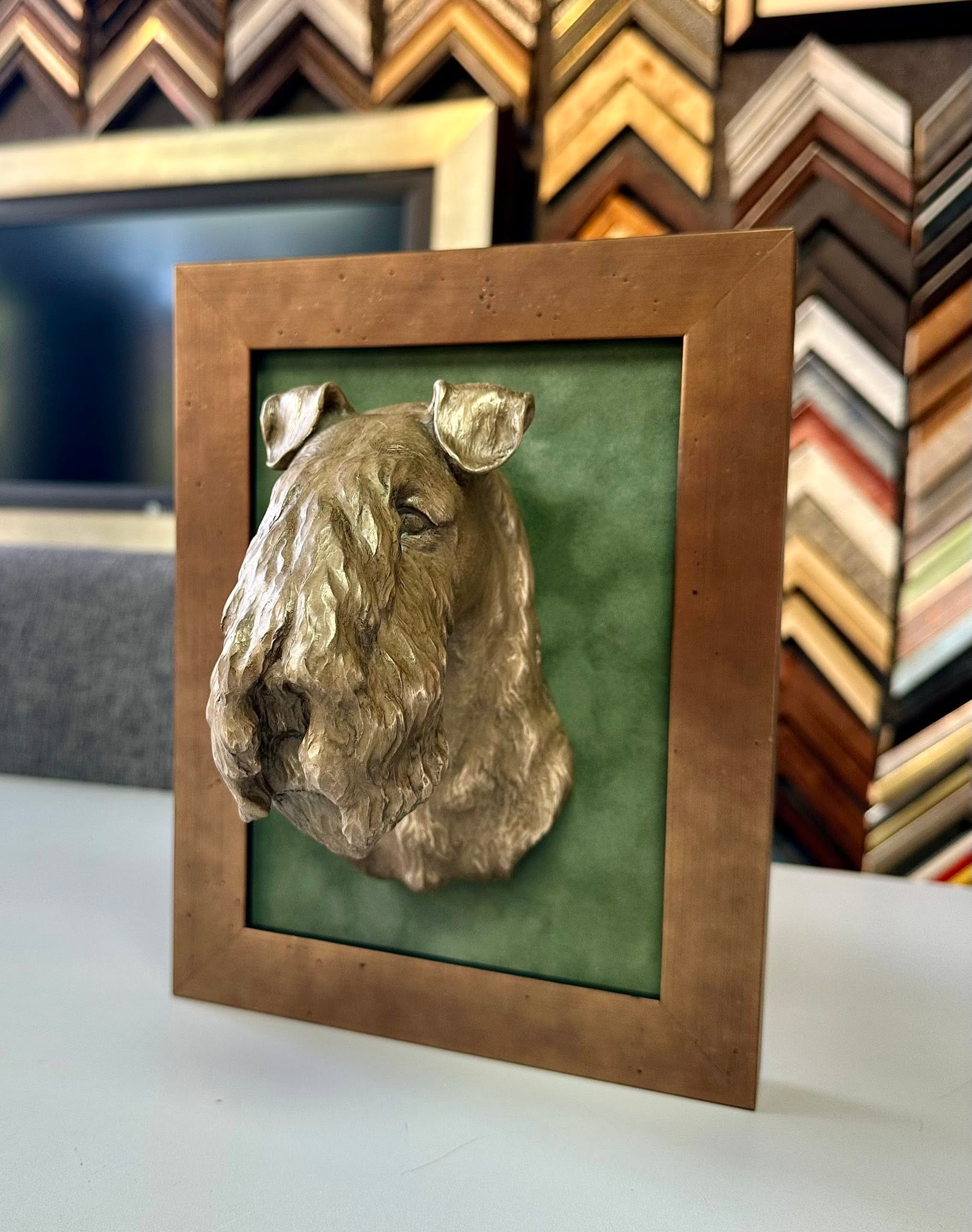 Custom framing for dog sculpture with bronze frame and green suede background